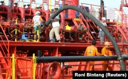 Pekerja memasang pipa untuk memompa minyak sawit mentah (CPO) ke kapal tanker di pelabuhan Belawan di Provinsi Sumatera Utara, 21 Februari 2013. (Foto: REUTERS/Roni Bintang)