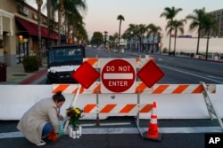 Stephanie Kozofsky (31), meninggalkan bunga dan lilin untuk menghormati para korban yang tewas dalam penembakan studio dansa ballroom hari Sabtu di Monterey Park, California, Minggu, 22 Januari 2023. (AP/Jae C. Hong)