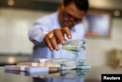 Seorang teller sedang menghitung uang rupiah di Jakarta, 27 Oktober 2014. (Foto: Reuters)