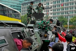 Anggota TNI membantu warga naik ke atas kendaraan lapis baja selama parade Hari Angkatan Bersenjata RI ke-77 di kawasan bisnis utama di Jakarta, Rabu, 5 Oktober 2022 (foto: dok).
