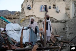 Warga Afghanistan berdiri di antara reruntuhan bangunan pascagempa bumi di desa Gayan, di provinsi Paktika, Afghanistan, Kamis, 23 Juni 2022. (AP/Ebrahim Nooroozi)