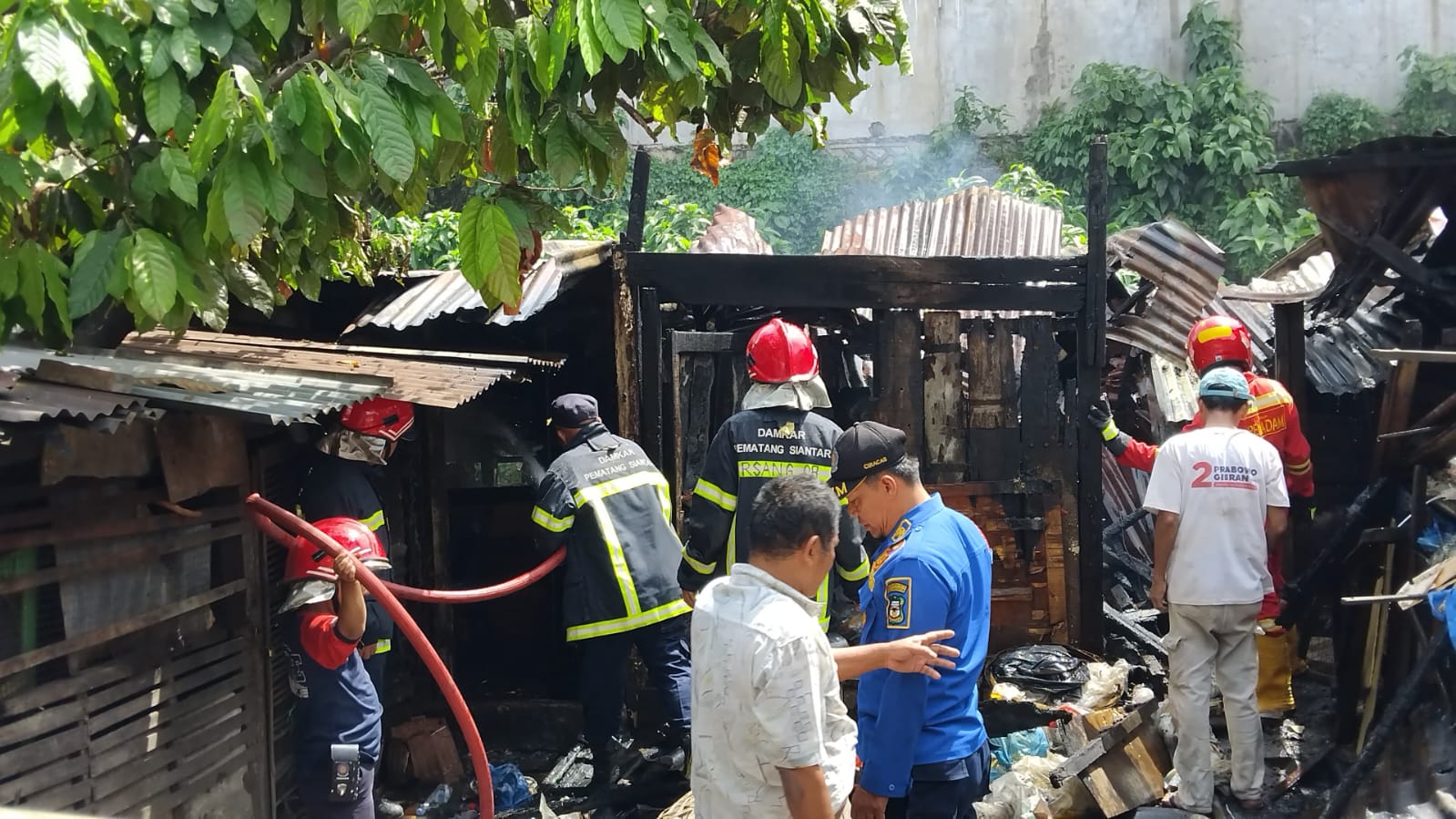Petugas pemadam kebakaran di lokasi kandang ternak babi yang terbakar. (foto:ist)