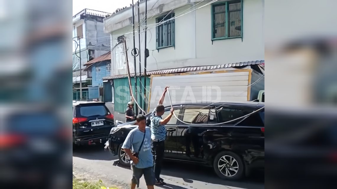 Warga berupaya mengangkat kabel yang menjuntai ke bawah. (foto:sinata)