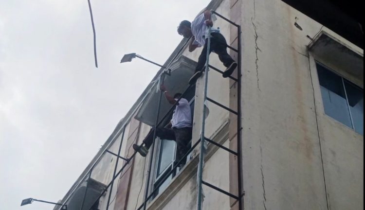 Dua pekerja saat  membantu proses eksekusi gedung di Jalan MH Sitorus, beraktivitas di ketinggian tanpa tali pengaman.