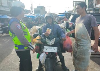 Kanit Kamsel IPDA Serly Tarigan bersama personil melaksanakan pembagian Brosur Tertib Berlalu Lintas dan Stiker Layanan Polisi 110 di Jalan Patuan Anggi