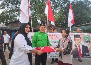 Ketua DPC PKB Kota Medan, Hamdan Simbolon, SH didampinggi anggota DPRD Kota Medan dari PKB, Lailatul Badri beserta sejumlah pengurus menyerahkan bendera merah putih kepada warga. (Foto Ist)