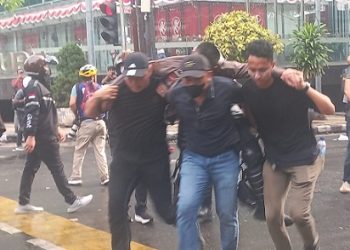 Sejumlah petugas berpakaian sipil membawa polisi yang terluka akibat kericuhan unjuk rasa di Gedung DPRD Sumut (Foto Romulo)