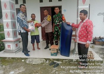 Bhabinkamtibmas Kelurahan Nagahuta Timur AIPDA F. Munthe melaksanakan pendampingan pembagian bantuan kepada warga terdampak bencana alam angin puting beliung di Jalan D.I Panjaitan Gang Pahala