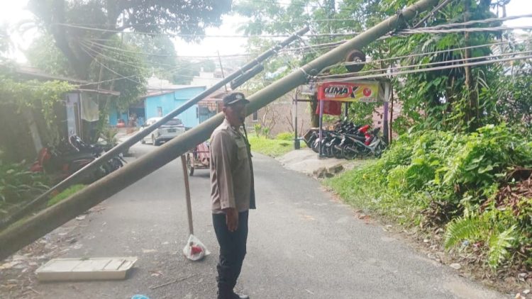 Bhabinkamtibmas Kelurahan Bantan Aiptu Rayendra P. Damanik pengecekan pohon bambu dan tiang listrik tumbang di Jalan Singosari