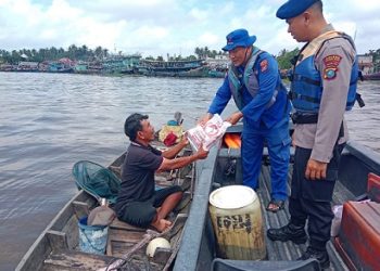 Personil Sat Polair saat membagikan rejeki kepada masyarakat nelayan