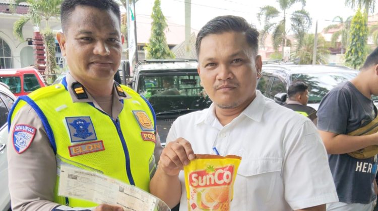 Kanit Regident IPTU Elon Sitinjak saat memberikan minyak goreng kepada pengendara Pengendara Langsung Bayar Pajak Kendaraan