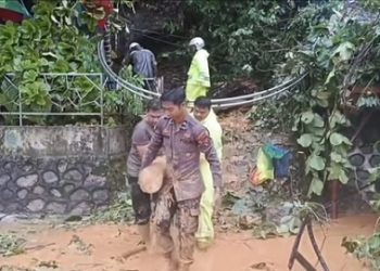 Personil kepolisian membantu warga membersihkan material lumpur akibat longsor yang terjadi. (Foto Ist)