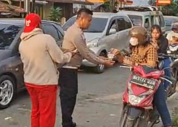 Kanit Regident IPTU Elon Sitinjak SH saat bagikan air mineral kepada pengendara antri BBM
