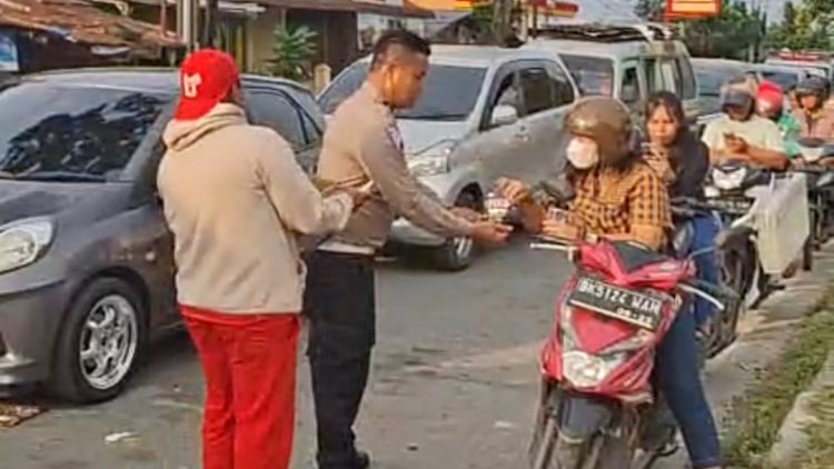 Kanit Regident IPTU Elon Sitinjak SH saat bagikan air mineral kepada pengendara antri BBM