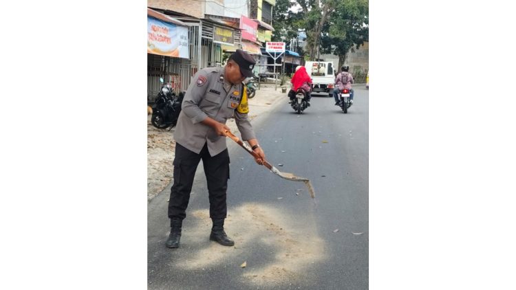 Bhabinkamtibmas Kelurahan Naga Pita Aipda A. Simatupang Tabur Pasir di Tumpahan Solar Jalan Rakutta Sembiring