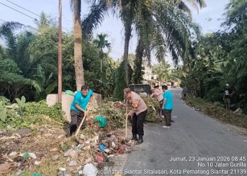Bhabinkamtibmas Kelurahan Bah Sorma AIPDA Fadlan Fahmi mengikuti gotong royong massal di Jalan Pisang Kipas