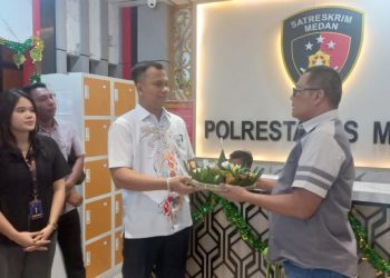 Advokat Tommy Aditia Sinulingga, SH, MH dan rekan menyerahkan nasi tumpeng kepada AKP Budiman Simanjuntak Wakasat Reskrim Polrestabes Medan. (Foto Romulo Sinaga)