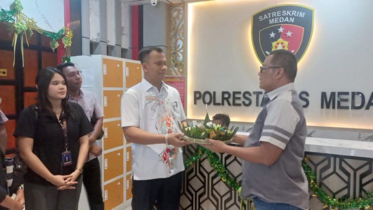 Advokat Tommy Aditia Sinulingga, SH, MH dan rekan menyerahkan nasi tumpeng kepada AKP Budiman Simanjuntak Wakasat Reskrim Polrestabes Medan. (Foto Romulo Sinaga)