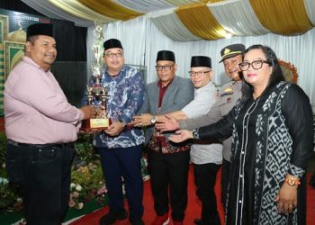 Asisten Administrasi Umum Setdako Dedy Tunasto Setiawan SH MH serahkan piala bergilir kepada Kelurahan Parhorasan Nauli sebagai juara umum