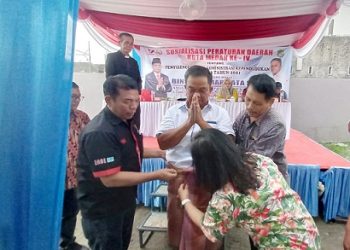 Anggota DPRD Kota Medan Binsar Simarmata saat menerima Hiou Pamotting dari pengurus dan pendeta GKPS Haleluya usai pelaksanaan Sosper Penyelenggaraan Administrasi Kependudukan. (Foto Ist)