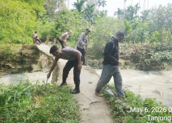 Kanit Binmas IPDA Nirwan Sirait bersama Bhabinkamtibmas ikut membantu pekerja/ tukang pembuatan Tiang Pengaman Jembatan Penghubung di Jalan Rindung