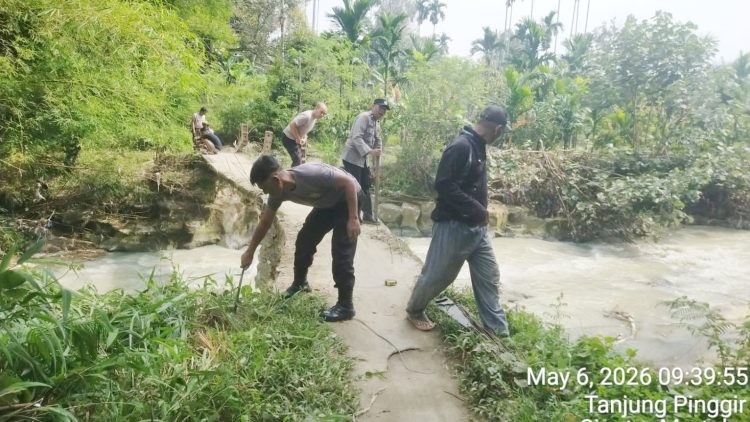 Kanit Binmas IPDA Nirwan Sirait bersama Bhabinkamtibmas ikut membantu pekerja/ tukang pembuatan Tiang Pengaman Jembatan Penghubung di Jalan Rindung