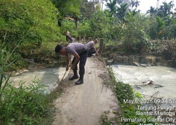 Kanit Binmas IPDA Nirwan Sirait bersama Bhabinkamtibmas ikut membantu pekerja/ tukang pembuatan Tiang Pengaman Jembatan Penghubung di Jalan Rindung