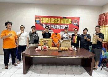 Tersangka PSS alias P dan barang bukti diapit Kanit 1 IPDA Hezron A. Simarmata S.Tr.I.K bersama Tim Opsnal di ruangan Sat Resnarkoba Polres Pematangsiantar