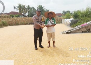 Bhabinkamtibmas Kelurahan Marihat Jaya Aiptu Erick F Marbun melakukan sambang dan monitoring petani binaan menjemur hasil panen jagung di Jalan Bahkora II