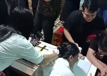 Yestin Laia ibunda dari Winda Lorenza Gowasa memeluk erat peti jenazah saat dilakukan proses pemakaman. (Foto Romulo Sinaga/jurnalx.co.id)