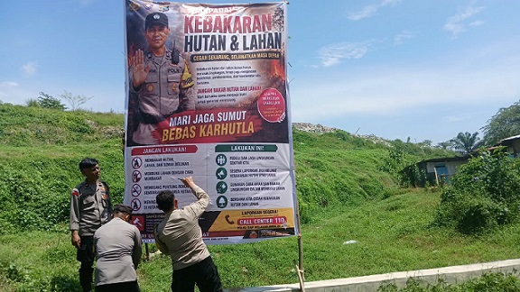 Kanit Binmas IPDA Nirwan Sirait bersama Bhabinkamtibmas AIPTU S. Ambarita, AIPTU Jonson Hutauruk dan AIPDA Nurdiansyah melakukan pemasangan spanduk waspada Karhutla di Jalan Rondahaim Saragih