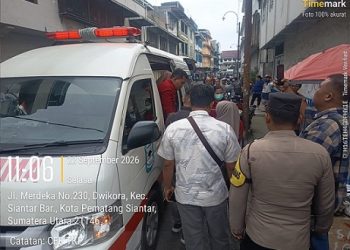 Personil piket Polsek Siantar Barat saat bantu seorang wanita yang pingsan disamping Toko Harum Manis
