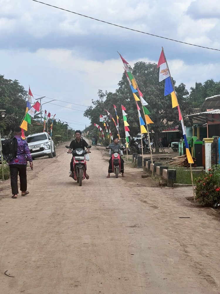 Warga dan kendaraan melintas di jalan poros Kecamatan Air Sugihan, Kabupaten OKI, yang tengah dibangun dan diperbaiki untuk meningkatkan konektivitas antar desa melalui sinergi pemerintah daerah, swasta, dan pemerintah desa.