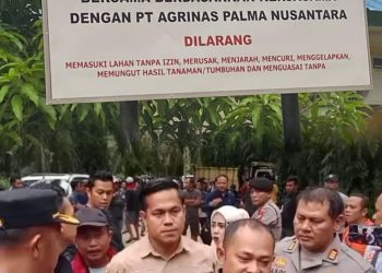 Sejumlah aparat kepolisian bersama perwakilan Kelompok Tani Kampar Jaya Bersama berada di depan papan pengumuman resmi pengelolaan lahan seluas 1.070 hektare di Desa Padang Mutung, Kecamatan Kampar. Kehadiran aparat menegaskan status hukum lahan yang telah disita negara dan diserahkan kepada kelompok tani melalui kerja sama dengan PT Agrinas Palma Nusantara.