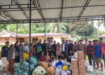 Sejumlah warga bersama relawan dan aparat setempat berfoto bersama saat proses penyerahan bantuan kemanusiaan untuk korban banjir di Aceh Tamiang. Beragam paket sembako, sayuran, air minum kemasan, serta kebutuhan dasar lainnya tampak tersusun di lokasi sebelum didistribusikan kepada masyarakat terdampak.