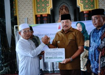 Bupati Nagan Raya Provinsi Aceh, Dr. TR. Keumangan, S.H., M.H., menyerahkan secara simbolis bantuan sajadah untuk masjid dan meunasah yang bersumber dari dana infak Baitul Mal Kabupaten Nagan Raya tahun 2025 senilai Rp400.000.000.