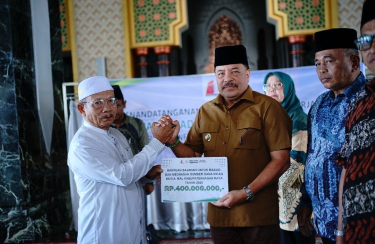 Bupati Nagan Raya Provinsi Aceh, Dr. TR. Keumangan, S.H., M.H., menyerahkan secara simbolis bantuan sajadah untuk masjid dan meunasah yang bersumber dari dana infak Baitul Mal Kabupaten Nagan Raya tahun 2025 senilai Rp400.000.000.