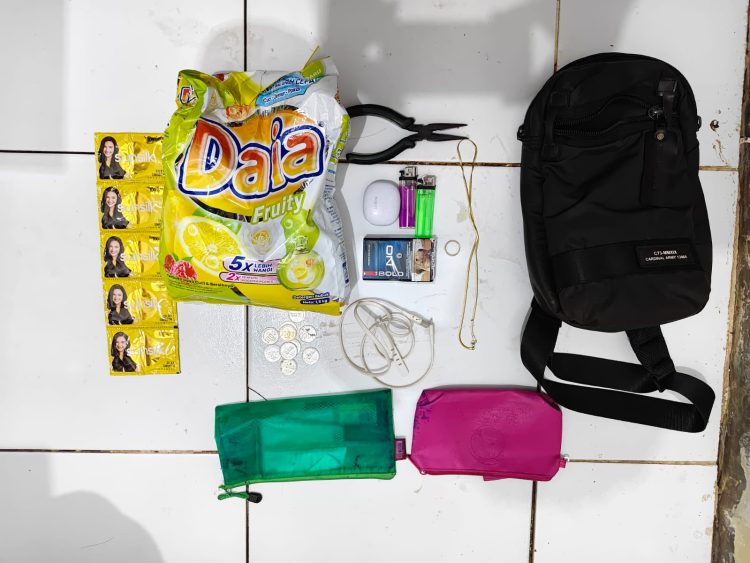 polisi turut mengamankan sejumlah barang bukti, di antaranya satu tas selempang warna cokelat, satu buah tang, dua korek api gas, satu bungkus rokok, headset Bluetooth TWS, kabel charger, perhiasan titanium, sabun cuci, sampo, hingga uang logam yang diduga sisa hasil pencurian.