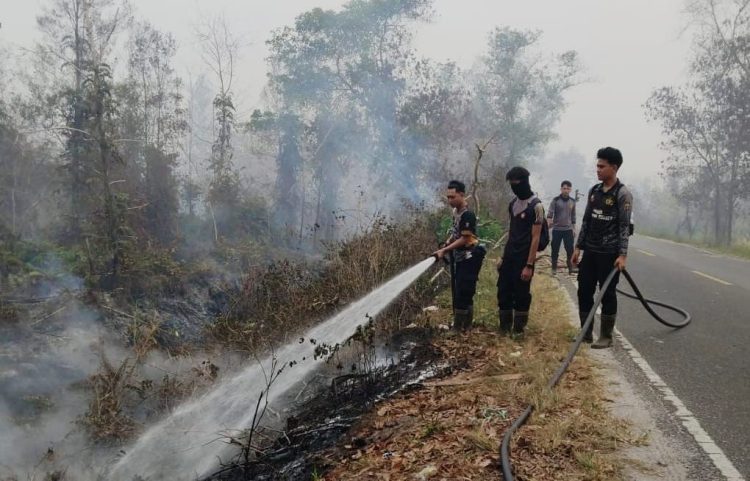 tengah kepulan asap karhutla personel Polda Kalteng terus berjibaku melakukan pemadaman dan pendinginan lahan gambut yang terbakar di kawasan Jl. Mahir Mahar Lingkar Luar,