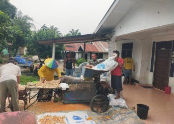 Babinsa Koramil 10/Tanah Jawa, Kodim 0207/Simalungun, Serka Suhadi, melaksanakan komunikasi sosial (komsos) sekaligus membantu proses penggilingan jagung hasil panen milik warga, Bapak Sumayanto, di Nagori Mekar Bahalat