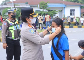 Kapolres Samosir AKBP Rina Sry Nirwana Tarigan, S.I.K., M.H., dengan membagikan masker kepada generasi muda dan para pengguna jalan di kawasan Simpang Empat Jalan Gereja, Pangururan, Kabupaten Samosir. (16/10/2026)