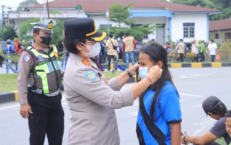 Kapolres Samosir AKBP Rina Sry Nirwana Tarigan, S.I.K., M.H., dengan membagikan masker kepada generasi muda dan para pengguna jalan di kawasan Simpang Empat Jalan Gereja, Pangururan, Kabupaten Samosir. (16/10/2026)