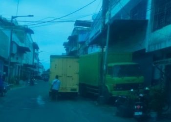 Truck Tronton dan Colt Diesel di badan Jalan Thamrin Pematangsiantar saat bongkar muat beras ganggu kelancaran berlalu lintas