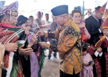 Bupati Anton saat menyematkan Hiou atau Ulos kepada kedua orangtua Wakil Ketua DPRD Bonauli Rajagukguk